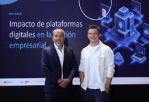 Siigo Aspel y la Asociación de Emprendedores de México (ASEM): digitalización empresarial impulsa ventas, productividad y competitividad Juan Carlos Cante, representante de la ASEM, y David Ortiz, CEO de Siigo Aspel, posan de pie lado a lado en un plano entero frente a una gran pantalla digital. Cante, a la izquierda, viste un traje sastre formal azul marino con camisa blanca de cuello abierto y mantiene las manos cruzadas al frente. Ortiz, a la derecha, posa sonriente con la mano izquierda en el bolsillo de su pantalón oscuro, vistiendo su camisa casual blanca. El fondo de la pantalla despliega el título del informe "Impacto de plataformas digitales en la gestión empresarial" flanqueado por gráficos isométricos en 3D de servidores, nube y analítica informática.