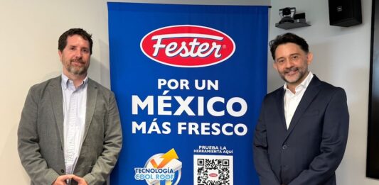 Fester y Google lanzan plataforma con IA para combatir las islas de calor urbano en México Fotografía en plano medio de estudio que muestra a dos ejecutivos de pie y sonrientes flanqueando una gran lona publicitaria de color azul brillante. El profesional de la izquierda, Sebastián Hiernaux de Google México, viste un saco gris claro sobre una camisa blanca de botones y pantalones de mezclilla; el directivo de la derecha, Vicente Madrid de Henkel, usa un traje sastre azul marino formal con camisa blanca. La mampara central despliega el logotipo ovalado de "Fester" en color rojo y blanco, seguido de la frase en letras blancas "POR UN MÉXICO MÁS FRESCO", un gráfico de la iniciativa "TECNOLOGÍA COOL ROOF" y un código QR grande con la leyenda "PRUEBA LA HERRAMIENTA AQUÍ".