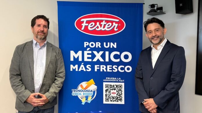 Fotografía en plano medio de estudio que muestra a dos ejecutivos de pie y sonrientes flanqueando una gran lona publicitaria de color azul brillante. El profesional de la izquierda, Sebastián Hiernaux de Google México, viste un saco gris claro sobre una camisa blanca de botones y pantalones de mezclilla; el directivo de la derecha, Vicente Madrid de Henkel, usa un traje sastre azul marino formal con camisa blanca. La mampara central despliega el logotipo ovalado de 
