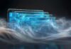 Cisco impulsa la infraestructura crítica con IA agéntica y seguridad en tiempo real Ilustración conceptual futurista que muestra una hilera de pantallas de cristal translúcido dispuestas de forma diagonal que brillan con luz azul cian. Los paneles flotantes despliegan circuitos electrónicos abstractos, flujos de datos lógicos e interfaces de usuario digitales, rodeados en la parte inferior por espirales de humo luminoso multicolor sobre un fondo oscuro.