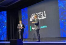 ESTELA: la IA no corrige datos deficientes y puede amplificar los riesgos fiscales de las empresas Fotografía en plano medio de Jair Martínez Aguilar, Country Manager de ESTELA en México, posando de pie y con los brazos cruzados en una oficina corporativa difuminada. El directivo es calvo, tiene barba corta y viste un saco de vestir color azul claro sobre una camisa blanca de cuello abierto. Porta anteojos de armazón negro grueso y mira con expresión seria y fija directamente hacia la cámara. Al fondo se aprecian sutilmente lámparas colgantes modernas de oficina y escritorios de trabajo con personal apenas perceptible.