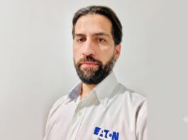 Eaton impulsa los UPS para infraestructura crítica con mayor disponibilidad, escalabilidad y eficiencia Fotografía de retrato en plano medio de Alejandro Lavín, Product Manager CPS de Eaton. El ejecutivo, de cabello oscuro, tez clara y barba, mira directamente a la cámara con una expresión neutral. Viste una camisa blanca de botones que lleva bordado el logotipo azul de la marca Eaton en el lado izquierdo del pecho, sobre un fondo liso de color gris claro.