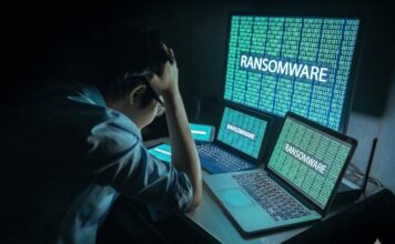 México, entre los países más afectados por el robo de identidad y el ransomware, alerta Sophos Fotografía que muestra a un administrador de TI visto desde atrás, sentado frente a su estación de trabajo en una habitación oscura y sosteniendo su cabeza con ambas manos en un gesto de frustración y estrés. Frente a él, tres pantallas alineadas (una tableta, una computadora portátil en primer plano y un monitor grande al fondo) despliegan simultáneamente código binario de color verde brillante sobre el cual resalta la palabra "RANSOMWARE" en letras mayúsculas blancas, bloqueando el acceso al sistema.