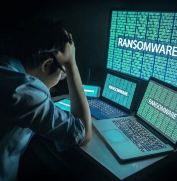 México, entre los países más afectados por el robo de identidad y el ransomware, alerta Sophos Fotografía que muestra a un administrador de TI visto desde atrás, sentado frente a su estación de trabajo en una habitación oscura y sosteniendo su cabeza con ambas manos en un gesto de frustración y estrés. Frente a él, tres pantallas alineadas (una tableta, una computadora portátil en primer plano y un monitor grande al fondo) despliegan simultáneamente código binario de color verde brillante sobre el cual resalta la palabra "RANSOMWARE" en letras mayúsculas blancas, bloqueando el acceso al sistema.
