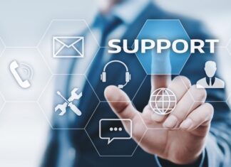 Vulnerabilidades y ransomware elevan el riesgo operativo para industrias estratégicas, advierte Kaseya Ilustración digital en la que un profesional de traje interactúa con una interfaz futurista de hexágonos flotantes. Su dedo índice presiona el botón azul con la palabra "SUPPORT", rodeado de iconos tecnológicos como un sobre de correo, un teléfono, herramientas de mantenimiento, unos auriculares con micrófono, un globo terráqueo, un globo de texto y la silueta de una persona.