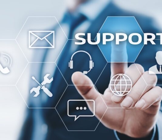 Vulnerabilidades y ransomware elevan el riesgo operativo para industrias estratégicas, advierte Kaseya Ilustración digital en la que un profesional de traje interactúa con una interfaz futurista de hexágonos flotantes. Su dedo índice presiona el botón azul con la palabra "SUPPORT", rodeado de iconos tecnológicos como un sobre de correo, un teléfono, herramientas de mantenimiento, unos auriculares con micrófono, un globo terráqueo, un globo de texto y la silueta de una persona.
