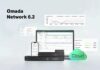 Omada Network 6.2 simplifica la gestión de redes empresariales con más automatización y seguridad Gráfico publicitario sobre un fondo degradado azul claro que muestra el título "Omada Network 6.2" en letras negras a la izquierda. Al centro se ubica una computadora portátil abierta junto a un teléfono inteligente en posición vertical, ambos desplegando el panel de control (dashboard) con gráficas analíticas de rendimiento de red. Delante de la computadora se apilan tres dispositivos de hardware en rack de color negro brillante con puertos Ethernet y entradas USB. A la derecha, resalta un gráfico circular tridimensional de color verde brillante con la palabra "Cloud" inscrita en color blanco, y en la parte superior flotan ventanas flotantes adicionales con métricas de tráfico y optimización WLAN.
