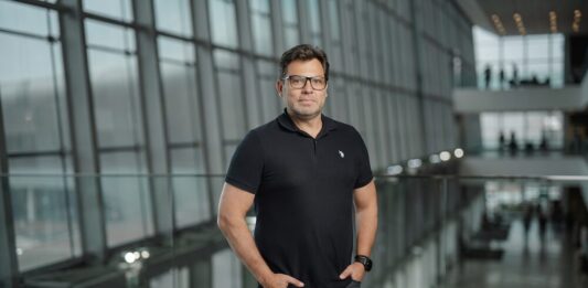 TOTVS destaca que la revisión del T-MEC impulsa la transformación digital de las empresas mexicanas Fotografía de Ivaldo Pereira, Head de TOTVS México, posando de frente con las manos en los bolsillos dentro de un moderno edificio corporativo con amplios ventanales de cristal. El ejecutivo usa anteojos, un reloj de pulsera oscuro y viste una playera tipo polo color negro.