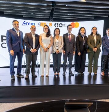 AMITI presenta “PyMEs Ciberseguras” para fortalecer la protección digital de empresas mexicanas Fotografía frontal de un grupo de ocho personas, conformado por hombres y mujeres en vestimenta formal de negocios, posando de pie y sonriendo sobre un escenario. A la izquierda del grupo hay un podio transparente que muestra el logotipo de Mastercard. En la parte trasera, una gran pantalla curva iluminada exhibe parte del texto del evento y los logotipos oficiales de AMITI, Capa 8, KIO IT Services y Mastercard.
