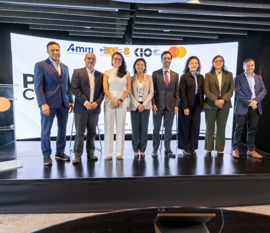 AMITI presenta “PyMEs Ciberseguras” para fortalecer la protección digital de empresas mexicanas Fotografía frontal de un grupo de ocho personas, conformado por hombres y mujeres en vestimenta formal de negocios, posando de pie y sonriendo sobre un escenario. A la izquierda del grupo hay un podio transparente que muestra el logotipo de Mastercard. En la parte trasera, una gran pantalla curva iluminada exhibe parte del texto del evento y los logotipos oficiales de AMITI, Capa 8, KIO IT Services y Mastercard.