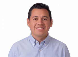 Hikvision impulsa una estrategia inteligente para la infraestructura crítica Fotografía de retrato de Xavier Arroyo, hombre de tez clara, cabello oscuro y corto, sonriendo directamente a la cámara. Viste una camisa de botones en tono azul claro y se encuentra sobre un fondo completamente blanco.