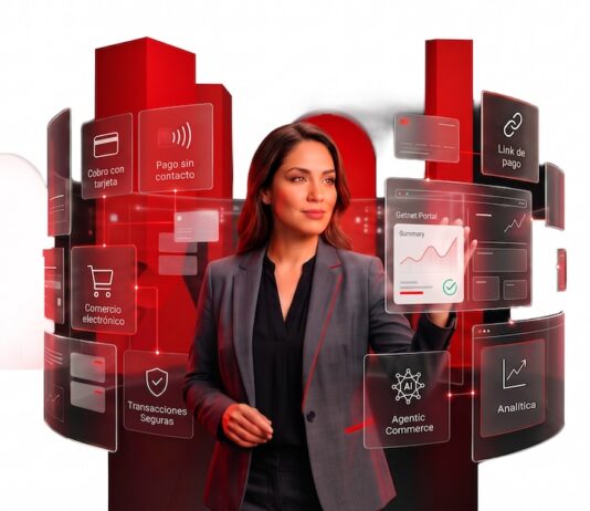 Getnet México transforma los pagos en motor de crecimiento empresarial Fotografía de una mujer con traje sastre gris interactuando con una interfaz holográfica que despliega paneles interactivos con opciones como "Cobro con tarjeta", "Pago sin contacto", "Comercio electrónico" y "Analítica". Al fondo se observan formas geométricas cilíndricas de color rojo brillante sobre un fondo blanco.