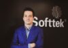 Softtek: el CIO redefine su rol y convierte la tecnología en una decisión económica Fotografía de medio cuerpo de Juan José D'Alessandro posando con los brazos cruzados. Viste una camisa de patrón claro y un saco azul, ubicado frente a un fondo oscuro donde destaca el logotipo corporativo de la empresa Softtek.