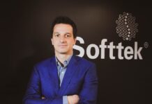 Softtek: el CIO redefine su rol y convierte la tecnología en una decisión económica Fotografía de medio cuerpo de Juan José D'Alessandro posando con los brazos cruzados. Viste una camisa de patrón claro y un saco azul, ubicado frente a un fondo oscuro donde destaca el logotipo corporativo de la empresa Softtek.