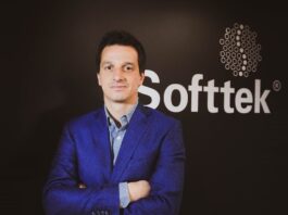Softtek: el CIO redefine su rol y convierte la tecnología en una decisión económica Fotografía de medio cuerpo de Juan José D'Alessandro posando con los brazos cruzados. Viste una camisa de patrón claro y un saco azul, ubicado frente a un fondo oscuro donde destaca el logotipo corporativo de la empresa Softtek.