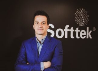 Softtek: el CIO redefine su rol y convierte la tecnología en una decisión económica Fotografía de medio cuerpo de Juan José D'Alessandro posando con los brazos cruzados. Viste una camisa de patrón claro y un saco azul, ubicado frente a un fondo oscuro donde destaca el logotipo corporativo de la empresa Softtek.