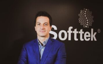 Softtek: el CIO redefine su rol y convierte la tecnología en una decisión económica Fotografía de medio cuerpo de Juan José D'Alessandro posando con los brazos cruzados. Viste una camisa de patrón claro y un saco azul, ubicado frente a un fondo oscuro donde destaca el logotipo corporativo de la empresa Softtek.