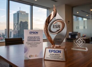 Epson México reafirma su compromiso con la sostenibilidad con el Distintivo ESR 2026 Fotografía de un premio metálico con el logotipo ESR y la inscripción CEMEFI sobre una mesa de juntas de madera. En la base del galardón se lee "EPSON MÉXICO RECEPTOR DESTACADO DEL DISTINTIVO ESR 2026". A su lado hay un folleto con el título "Epson México: Liderando con sostenibilidad" y un bloque de cristal decorativo. Al fondo, a través del amplio ventanal de la oficina, se aprecia la silueta del edificio del World Trade Center en la Ciudad de México durante el atardecer.