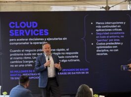 KIO IT Services revela las lecciones tecnológicas que dejó el Mundial 2026 Fotografía de Bruno Juanes hablando por micrófono frente a una pantalla oscura de presentación que resalta el texto "CLOUD SERVICES" y sus beneficios operativos, mientras miembros de la audiencia lo escuchan y graban con sus teléfonos móviles.