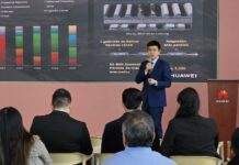 Huawei impulsa la inteligencia artificial y el almacenamiento solar para la industria en México Fotografía de una presentación ejecutiva donde Zhou Bo habla con un micrófono de mano ante un auditorio. De fondo se aprecia una pantalla proyectora con gráficos estadísticos, mapas de plantas BESS y el logotipo corporativo de Huawei.