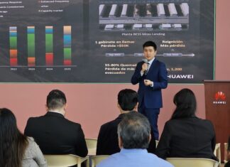 Huawei impulsa la inteligencia artificial y el almacenamiento solar para la industria en México Fotografía de una presentación ejecutiva donde Zhou Bo habla con un micrófono de mano ante un auditorio. De fondo se aprecia una pantalla proyectora con gráficos estadísticos, mapas de plantas BESS y el logotipo corporativo de Huawei.