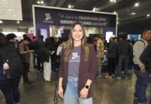El poder de DataDog para asegurar el futuro de la inteligencia artificial empresarial Fotografía en plano medio de Queennie López, Senior Alliances Manager para Datadog en México, sonriendo frente al estand de la marca en un evento tecnológico con el lema "IA para la observabilidad, OBSERVABILIDAD para la IA" al fondo.
