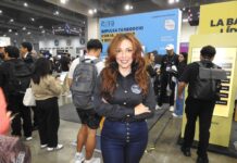 El futuro del sector enterprise está en la nube y la inteligencia artificial junto a Itera Fotografía en plano medio de Alondra Castro, Key Account Manager en Itera, sonriendo con los brazos cruzados en una camisa negra corporativa y jeans azules, frente al estand de la empresa en una convención tecnológica con el mensaje "IMPULSA TU NEGOCIO CON IA" al fondo.