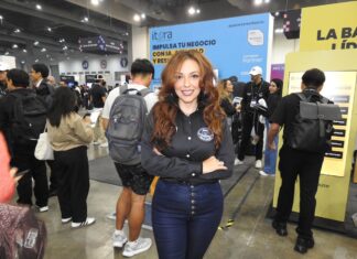El futuro del sector enterprise está en la nube y la inteligencia artificial junto a Itera Fotografía en plano medio de Alondra Castro, Key Account Manager en Itera, sonriendo con los brazos cruzados en una camisa negra corporativa y jeans azules, frente al estand de la empresa en una convención tecnológica con el mensaje "IMPULSA TU NEGOCIO CON IA" al fondo.