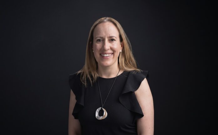 Ana María Ponce de León destaca el impacto de la IA en la gestión de gastos y toma de decisiones financieras Fotografía de retrato corporativo en plano medio de Ana María Ponce de León, CFO de Mendel, vestida con blusa negra sin mangas de holanes y collar metálico circular, sonriendo frente a un fondo negro neutro.