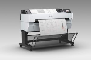 Fotografía en render de producto en vista de tres cuartos del plotter multifuncional Epson SureColor T5470M de 36 pulgadas con base de rodillos, mostrando la salida de un plano arquitectónico técnico en papel continuo.