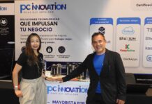 PC Software y la revolución tecnológica que redefine el sector enterprise Fotografía en plano medio de Nadia González y Eleazar Carrillo posando juntos detrás del mostrador corporativo de PC Innovation en un evento de la industria tecnológica.