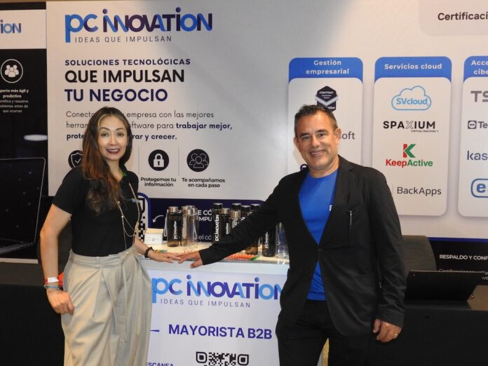 Equipo directivo de PC Software promueve soluciones de infraestructura escalable y ciberseguridad Fotografía en plano medio de Nadia González y Eleazar Carrillo posando juntos detrás del mostrador corporativo de PC Innovation en un evento de la industria tecnológica.