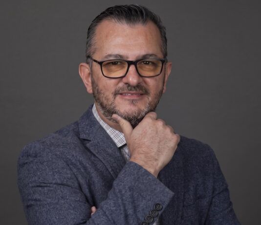 EPAM NEORIS: En la industria cementera, ese costo se refleja en accidentes, paros de planta e inventario perdido Fotografía de retrato en plano medio de Gilberto Quintanilla, Director Asociado y Líder de Visión por Computadora en EPAM NEORIS, vistiendo atuendo ejecutivo y posando en un entorno corporativo.