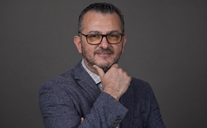 Fotografía de retrato en plano medio de Gilberto Quintanilla, Director Asociado y Líder de Visión por Computadora en EPAM NEORIS, vistiendo atuendo ejecutivo y posando en un entorno corporativo.