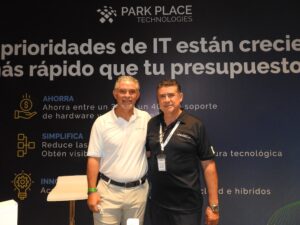 Fotografía en plano medio de Rogelio Moncada, Director Comercial de Park Place Technologies, y David Grajales, Presidente de Anadic Mx, posando juntos de pie y sonrientes frente al muro corporativo de Park Place Technologies.